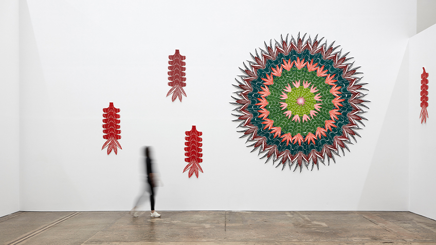 A blurred figure walks past Teho Ropeyarn's prints on a white wall within Carriageworks.
