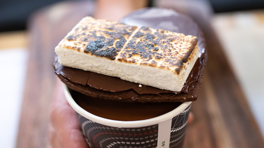 Chocolate Artisan hot chocolate with vanilla marshmallow and spiced cacao husk biscuit on top.