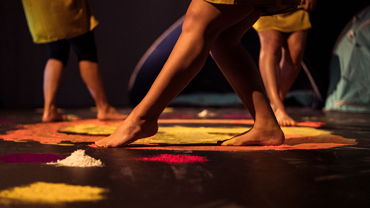 Dance performance with colourful pigment powder on the stage.