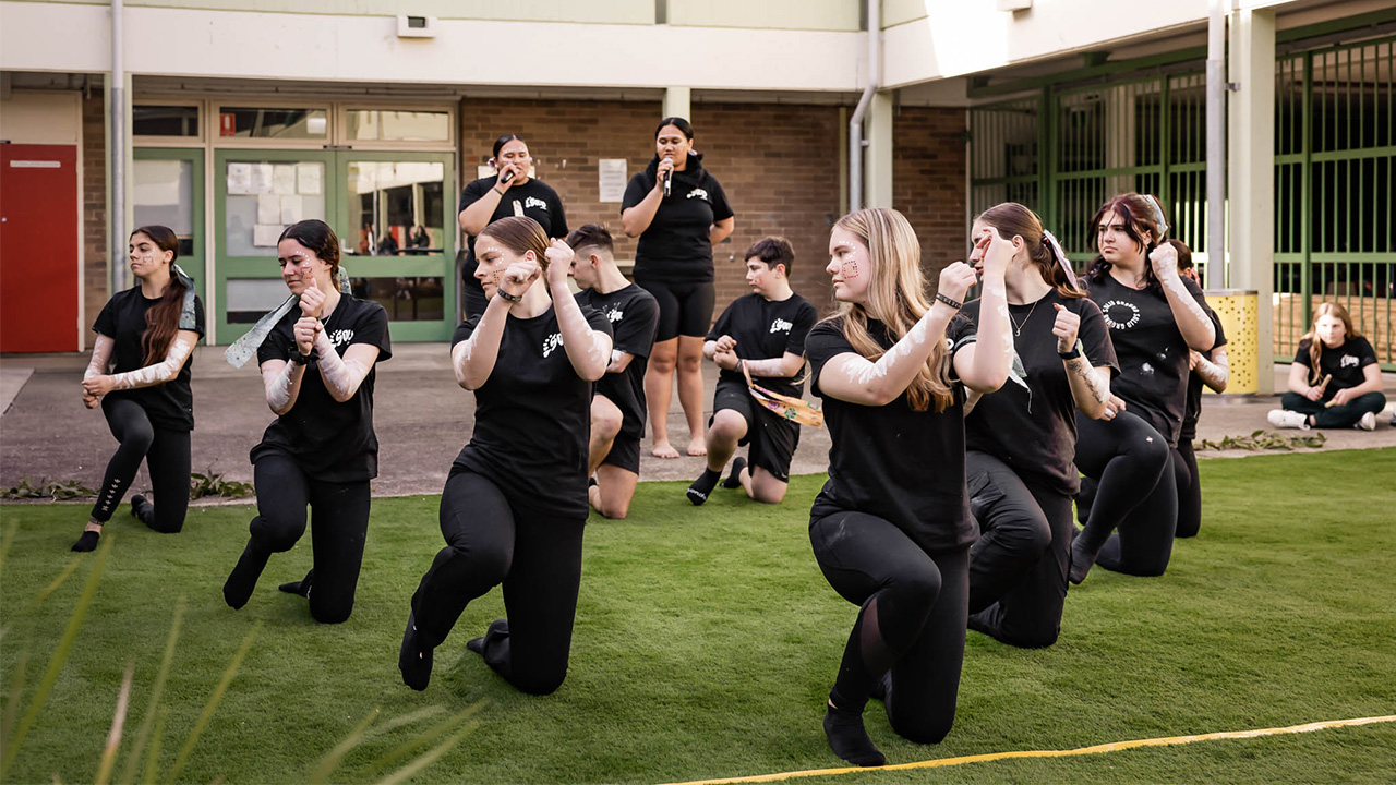 students wearing black dancing on grass