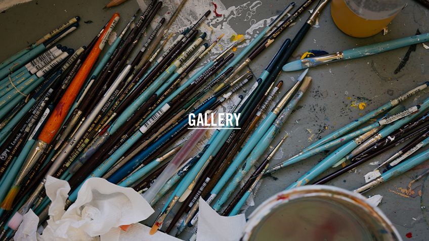 A shot of paintbrushes on a workbench. The word 'Gallery' is overlaid.