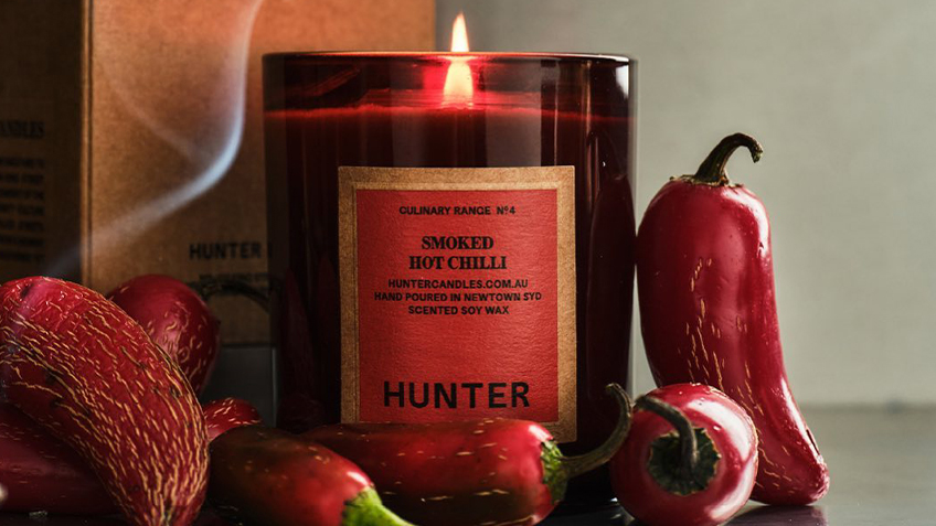 A Hunter Smoked Hot Chilli candle next to red chillis