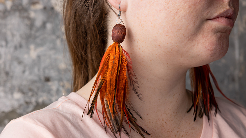 Earring with bead and orange feathers by artists Nannette Shaw and Fiona Hughes - available at Carriageworks' SOUTHEAST Aboriginal Arts Market 2022.