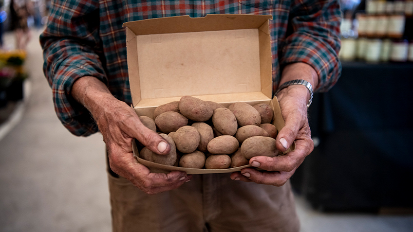 Man holds box of potatoes. Image credit Jacquie Manning