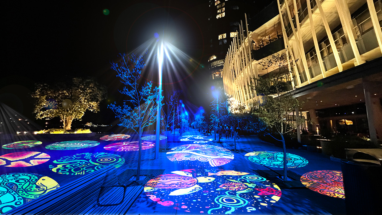 Render of Wulugal Walk at Crown Sydney with round artworks projected along the footpath.