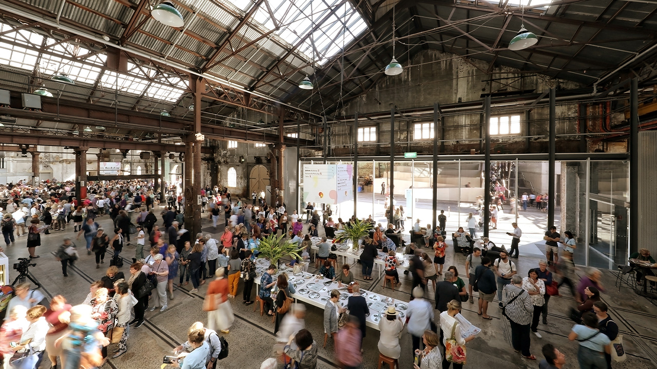 A blurred crowd gathers in the Public Space of Carriageworks for Sydney Writers' Festival