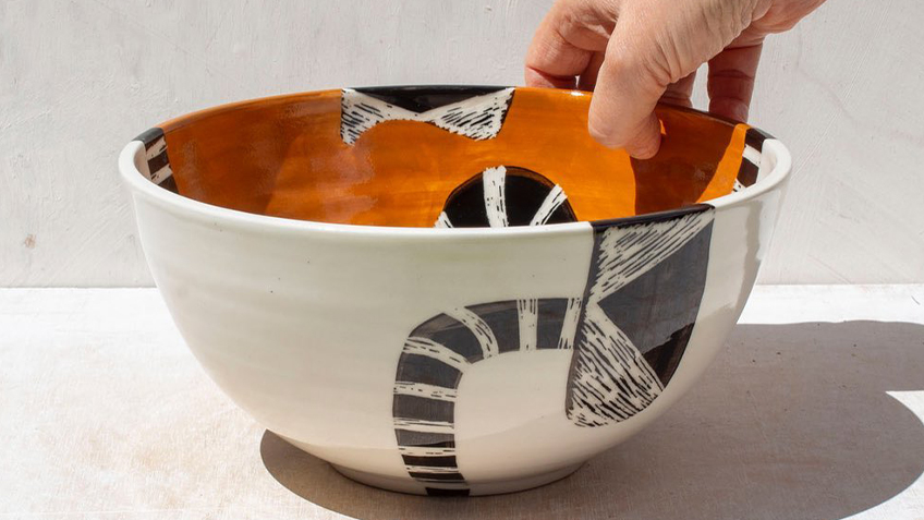A hand touches a ceramic bowl