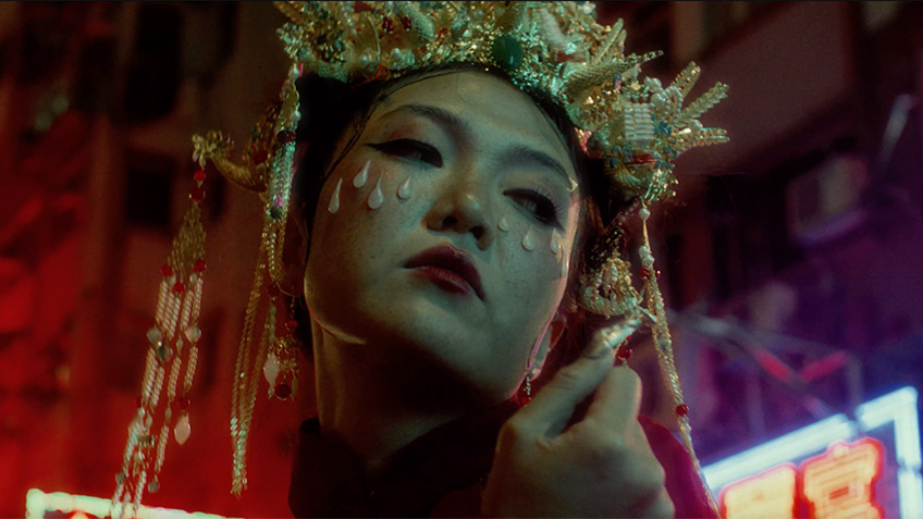 A close up of a woman's face. She is wearing a radiational Cantonese headdress.